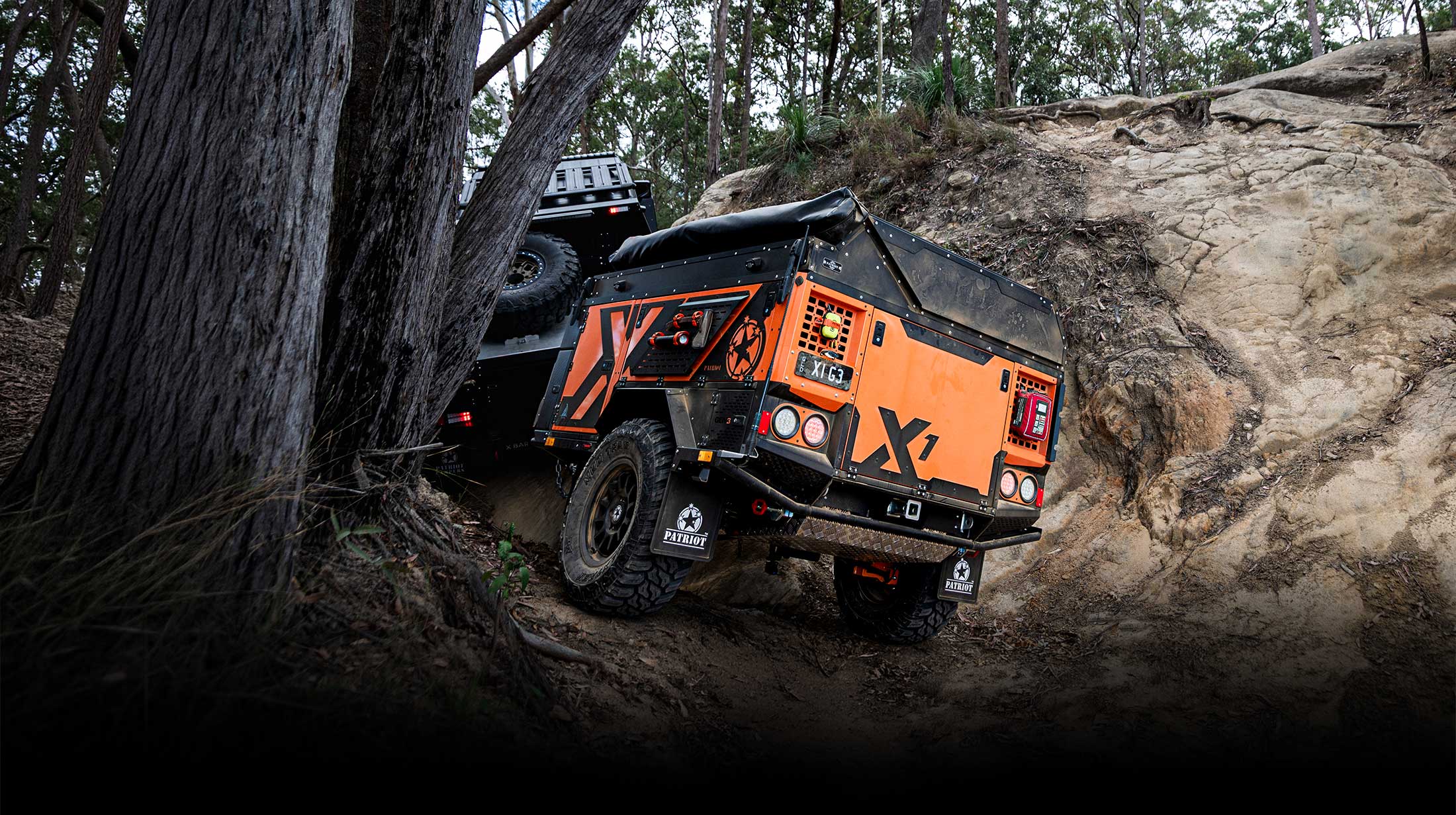 Orange Gen3 X1 and Jeep tackling a rocky forest track